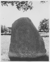 Runsten med kristen symbol på kyrkogården